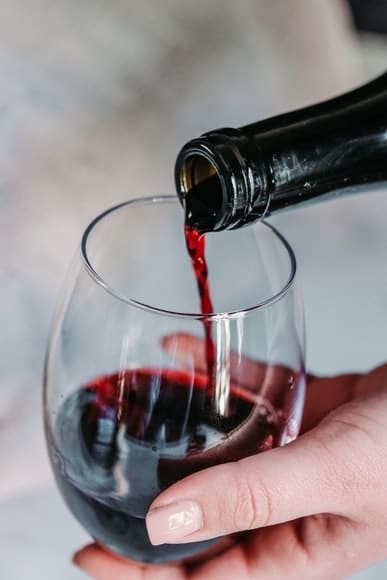 red-wine-hearing-loss A glass of red wine being poured from a bottle.