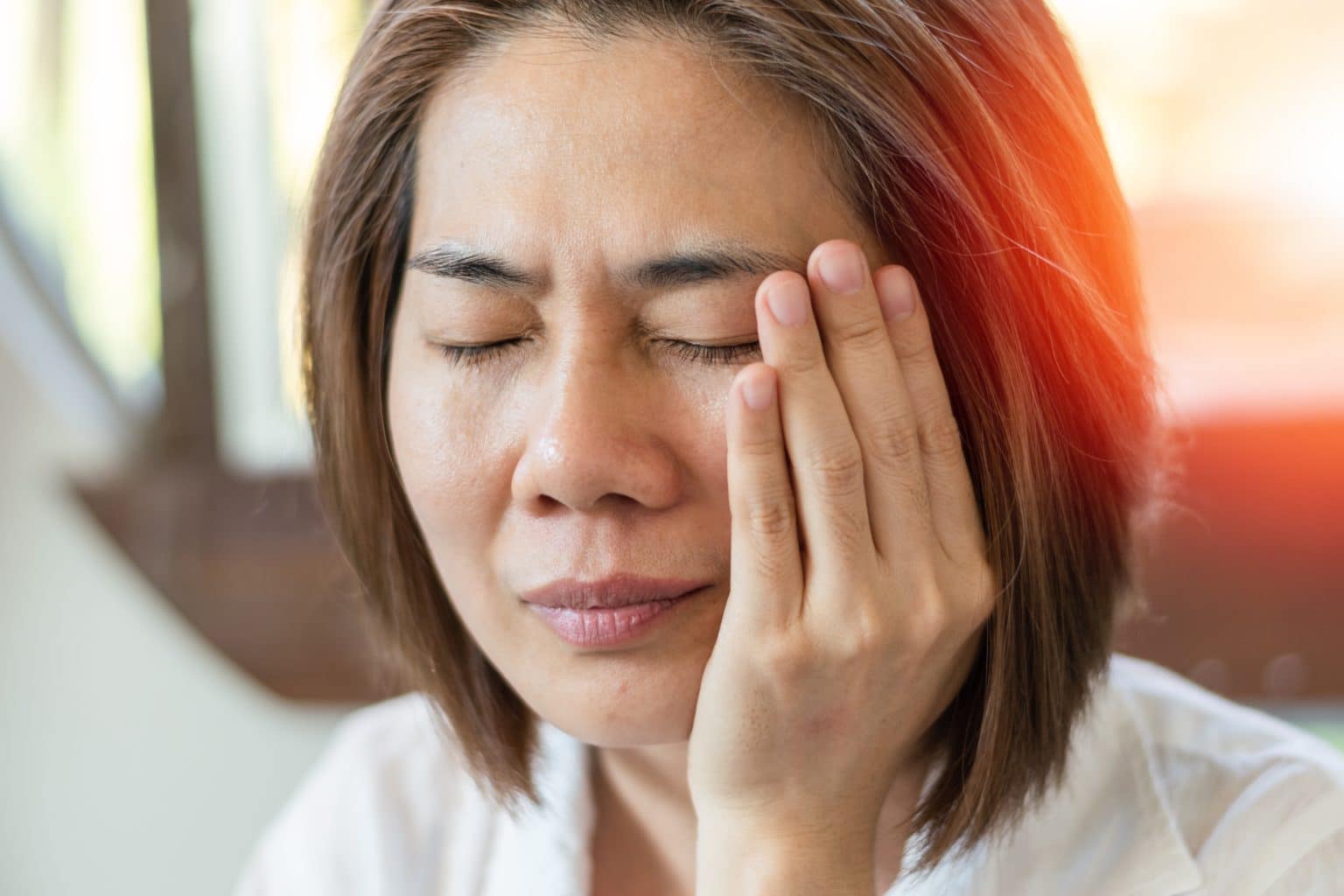 a woman in discomfort touches her face