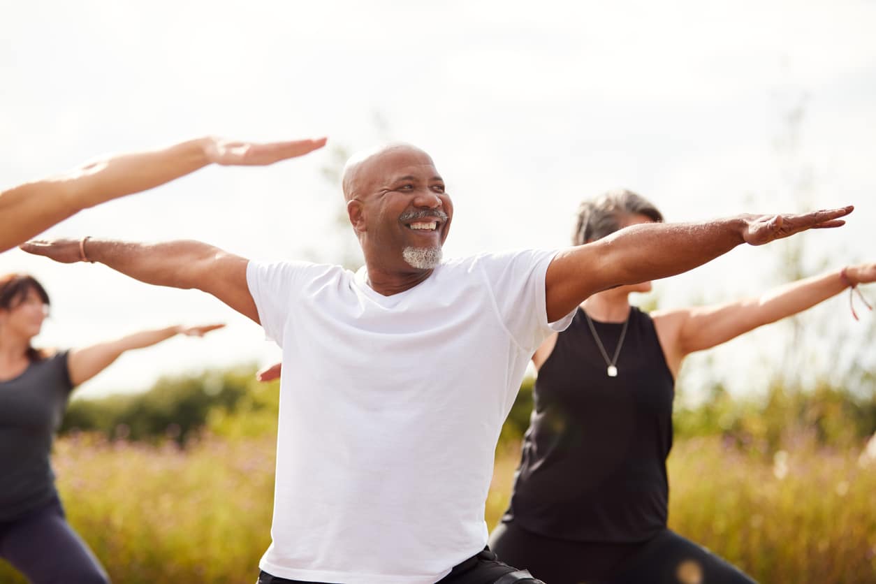 Man doing yoga outdoors with a group