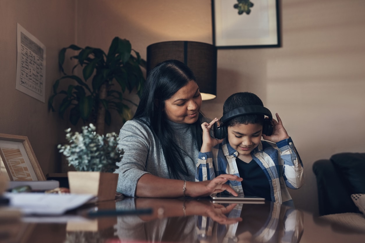 Mom and young boy listening and following along with an audiobook