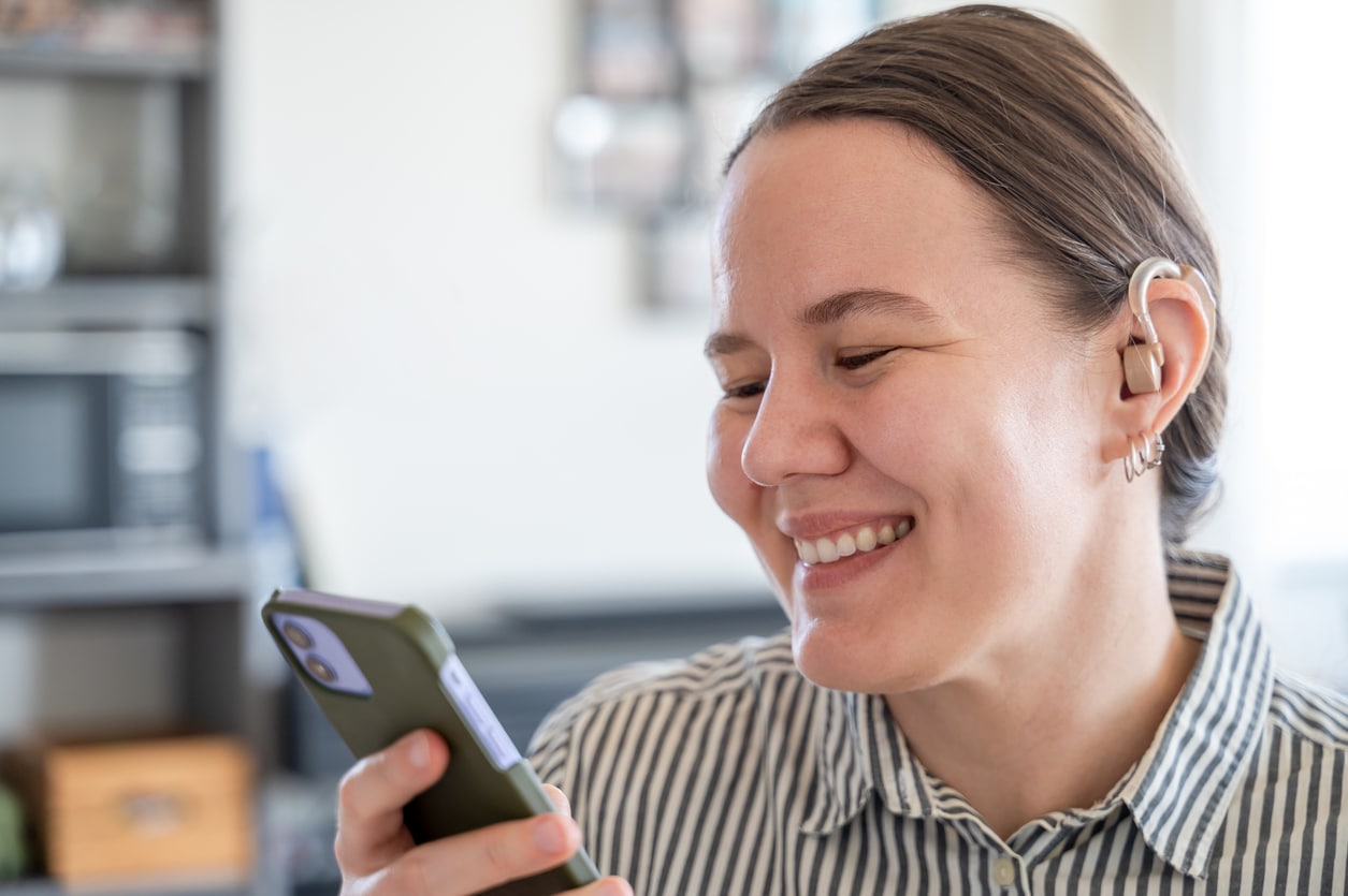 Woman smiles wearing hearing aid