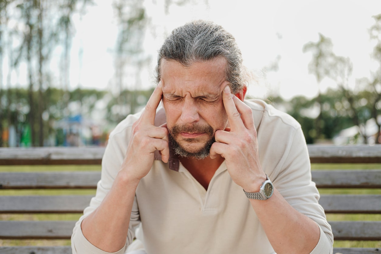 Annoyed man with tinnitus holding his temples. 