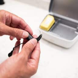 Person holding their charging hearing aid