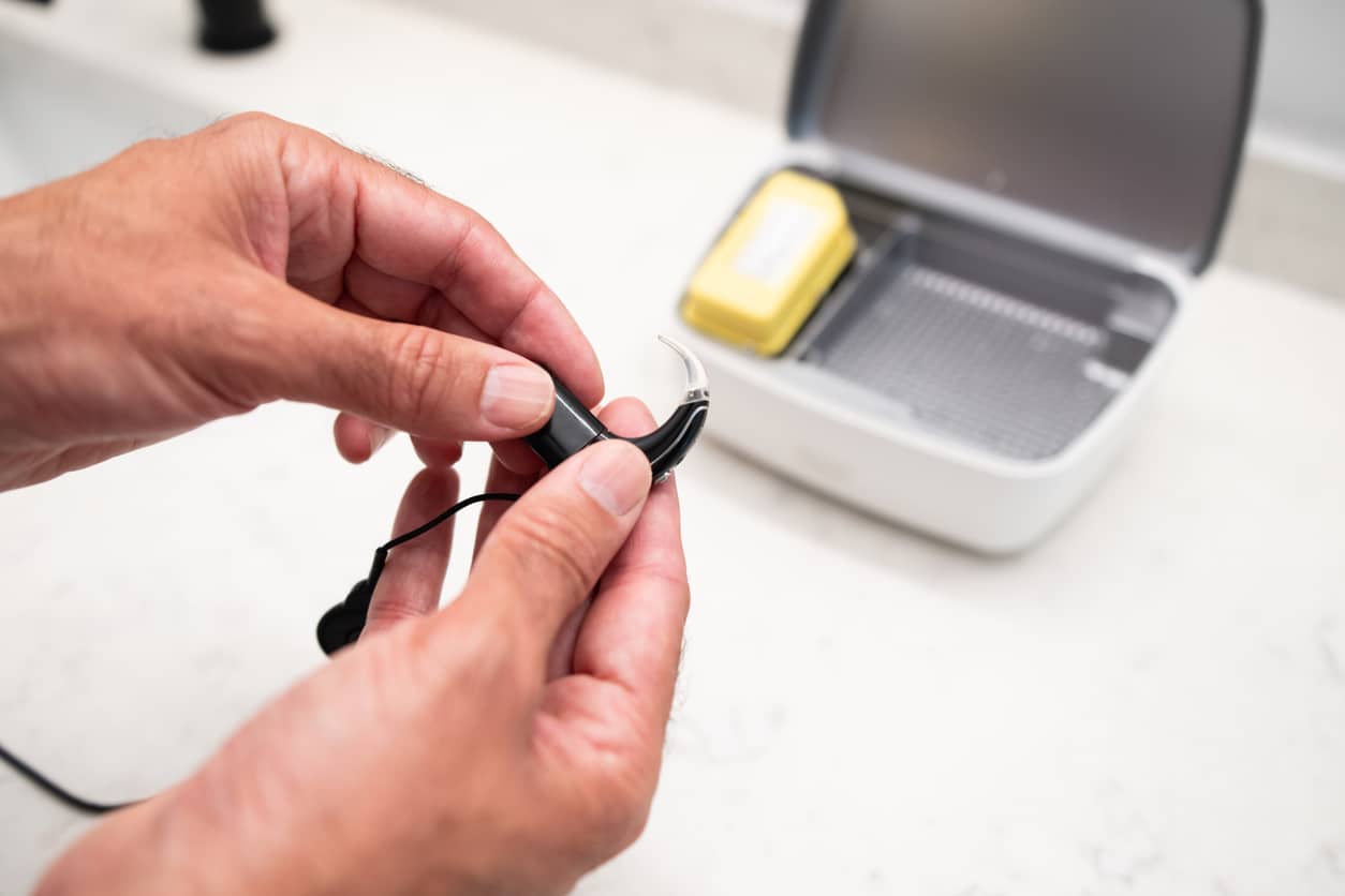 Person holding their charging hearing aid.