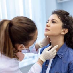 A woman gets her thyroid checked by an ENT doctor.